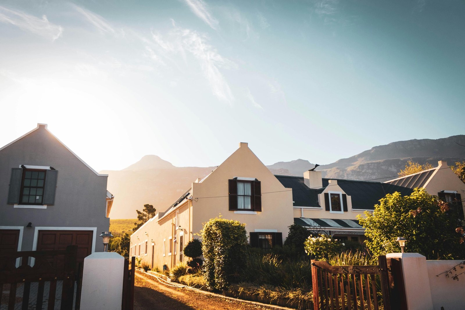 Immigration A picturesque countryside house under a vibrant sunset with mountain backdrop.