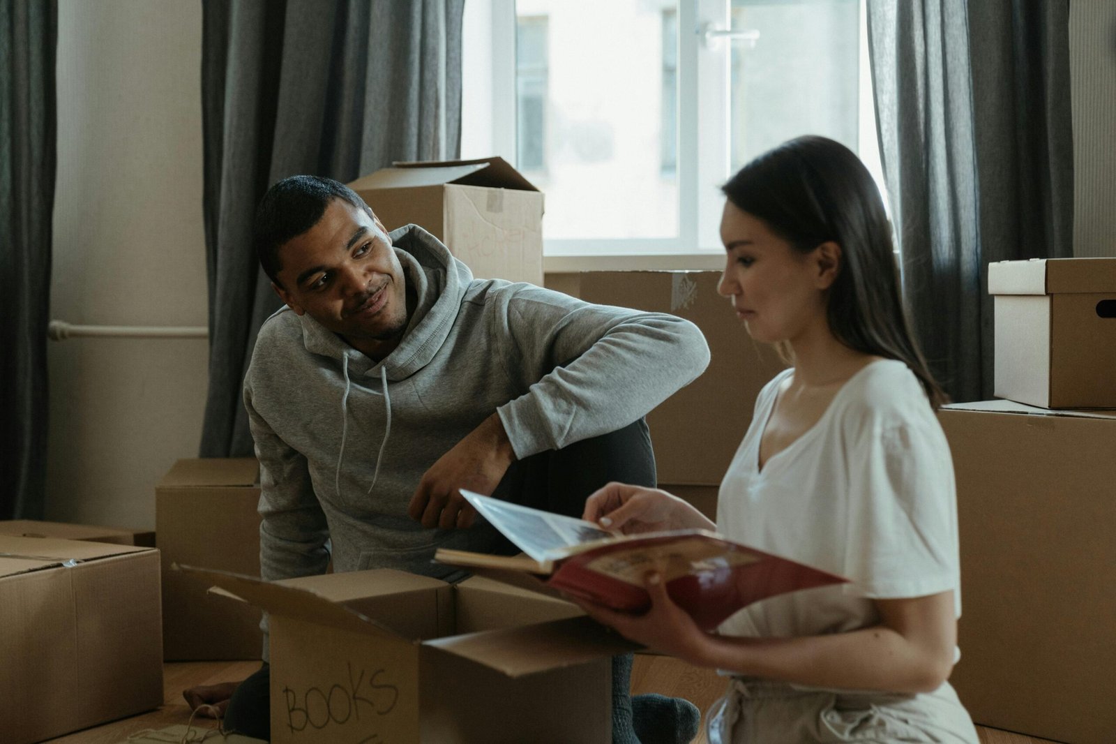 Immigration A couple exploring their new home while unpacking boxes and looking at a photo album.