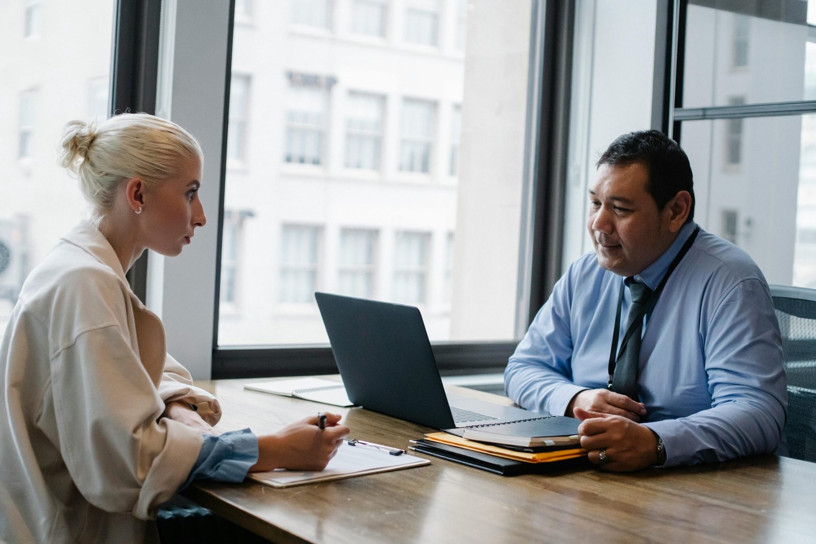Immigration Ethnic boss asking question to female candidate filling information form on clipboard during hiring meeting